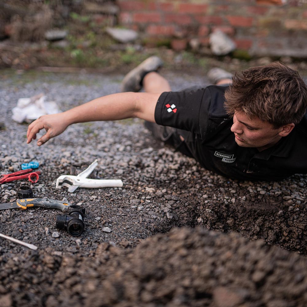 Plumber lying on ground working on drains