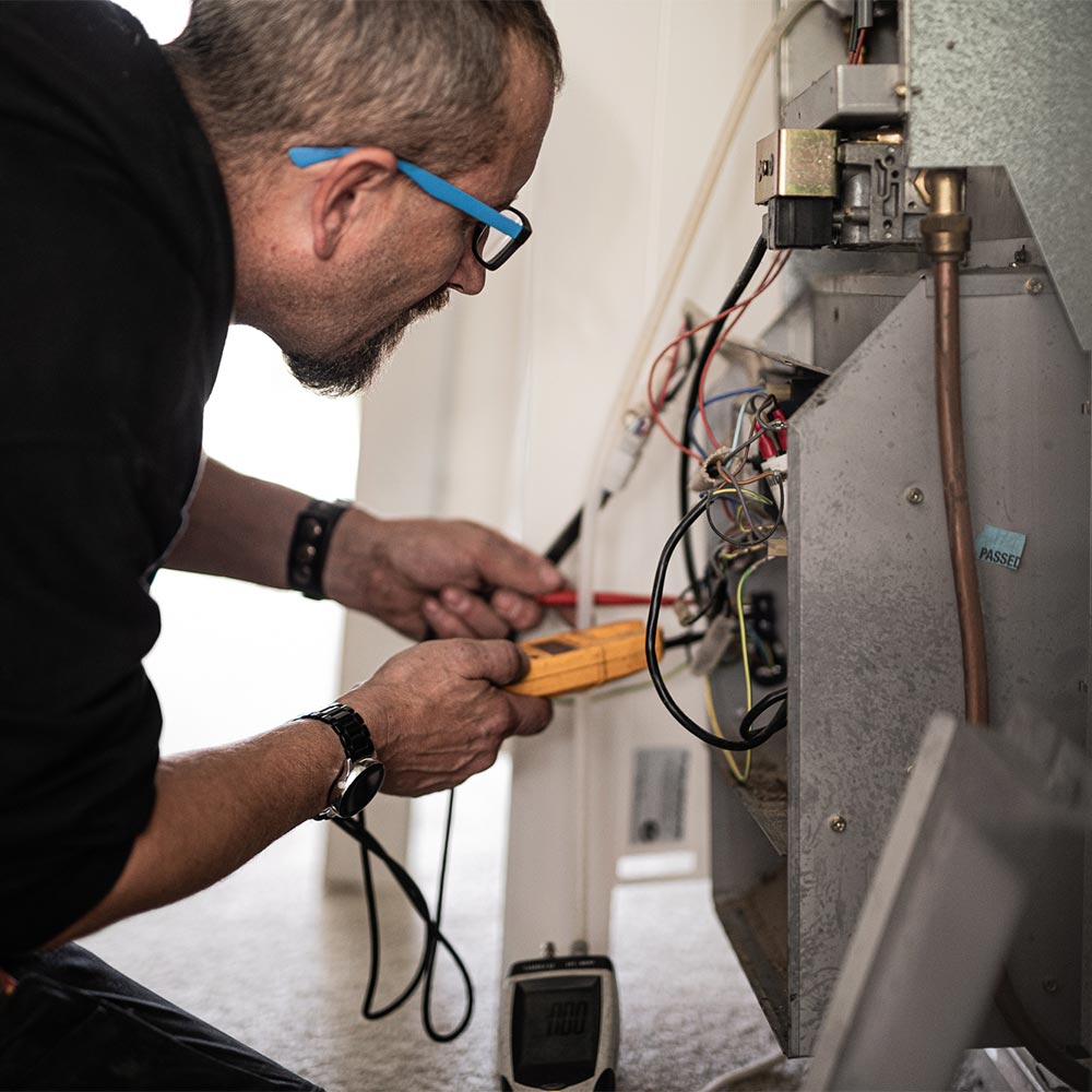Plumber working on indoor heating electrics