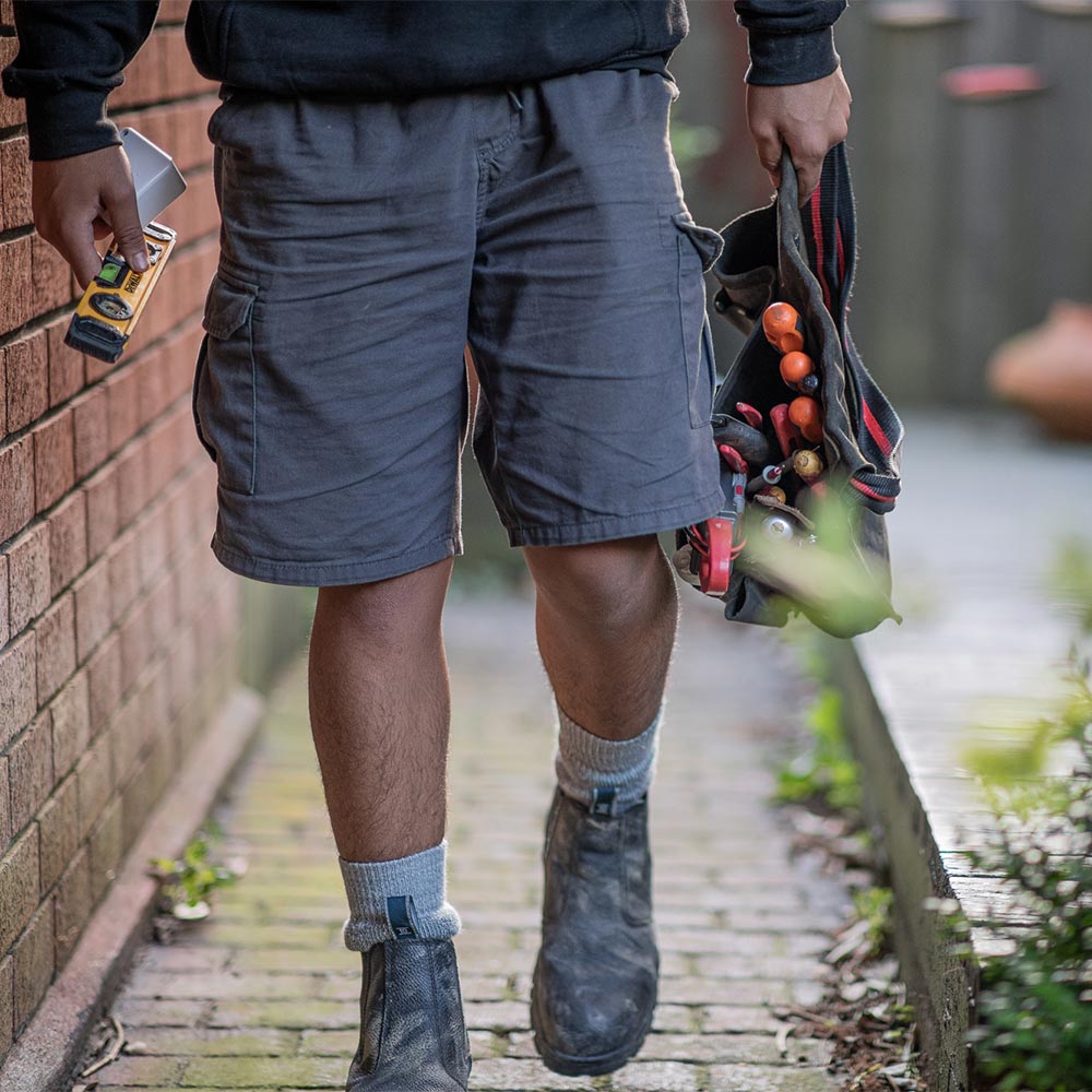 Plumber walking down side of house with tools